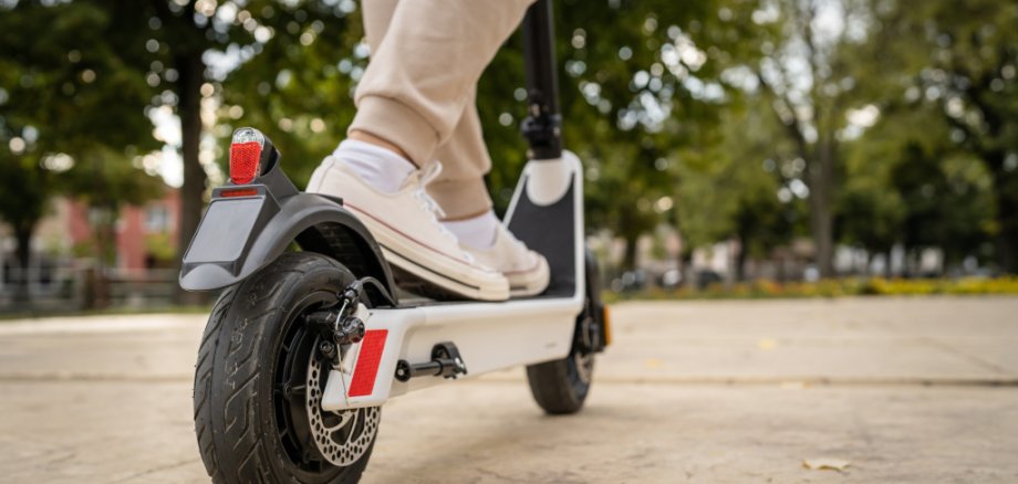 unknown man standing or driving electric kick scooter e-scooter Ausschnitt Person auf E-Scooter