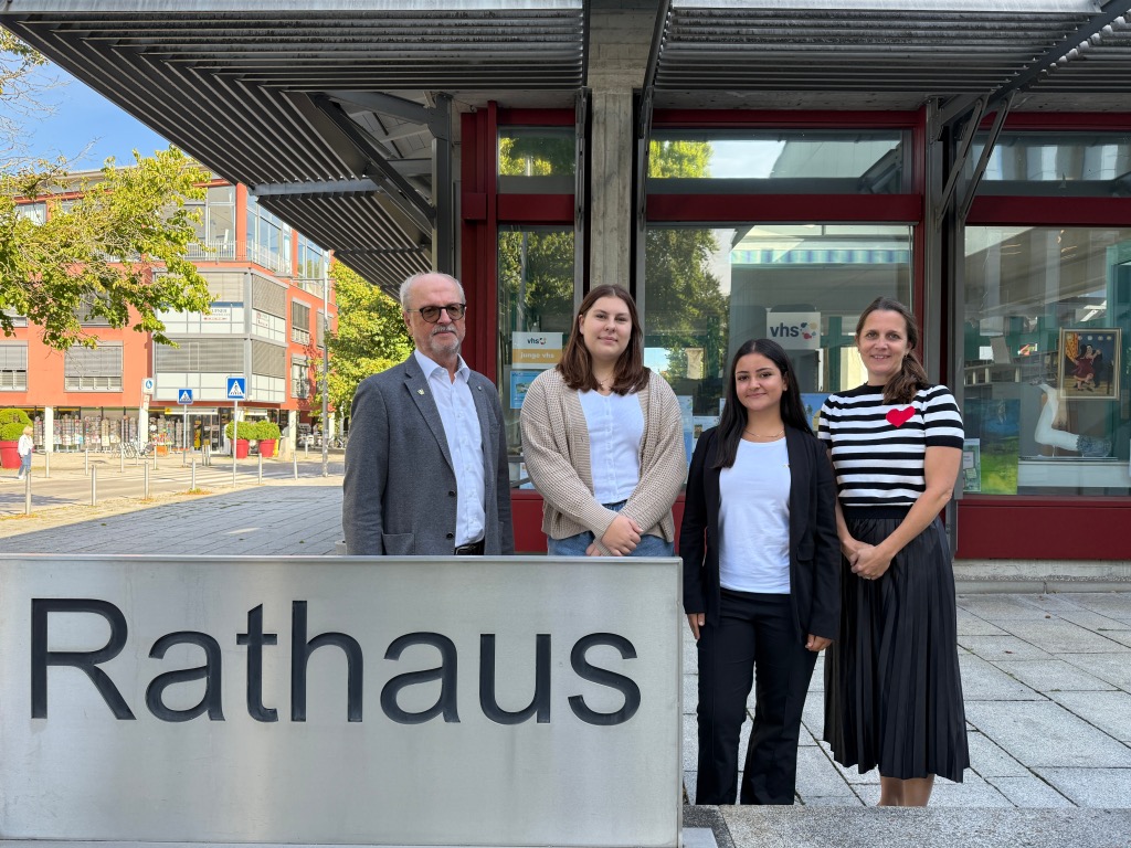 ein Mann und drei Frauen am Rathaus-Schild