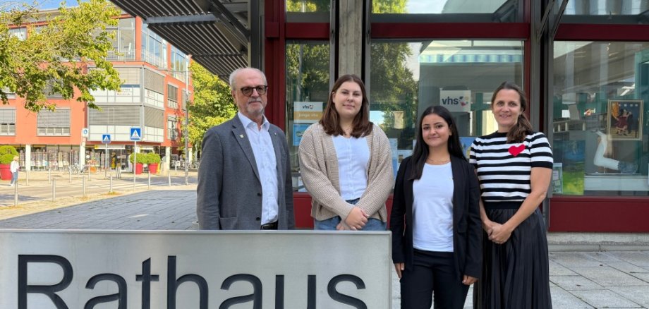 ein Mann und drei Frauen am Rathaus-Schild